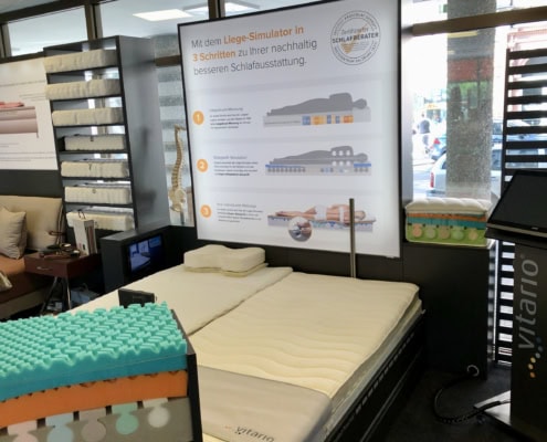Bettenhaus Schlafoase in Nürnberg zeigt eine Matratze mit Liege-Simulator und Informationsposter.