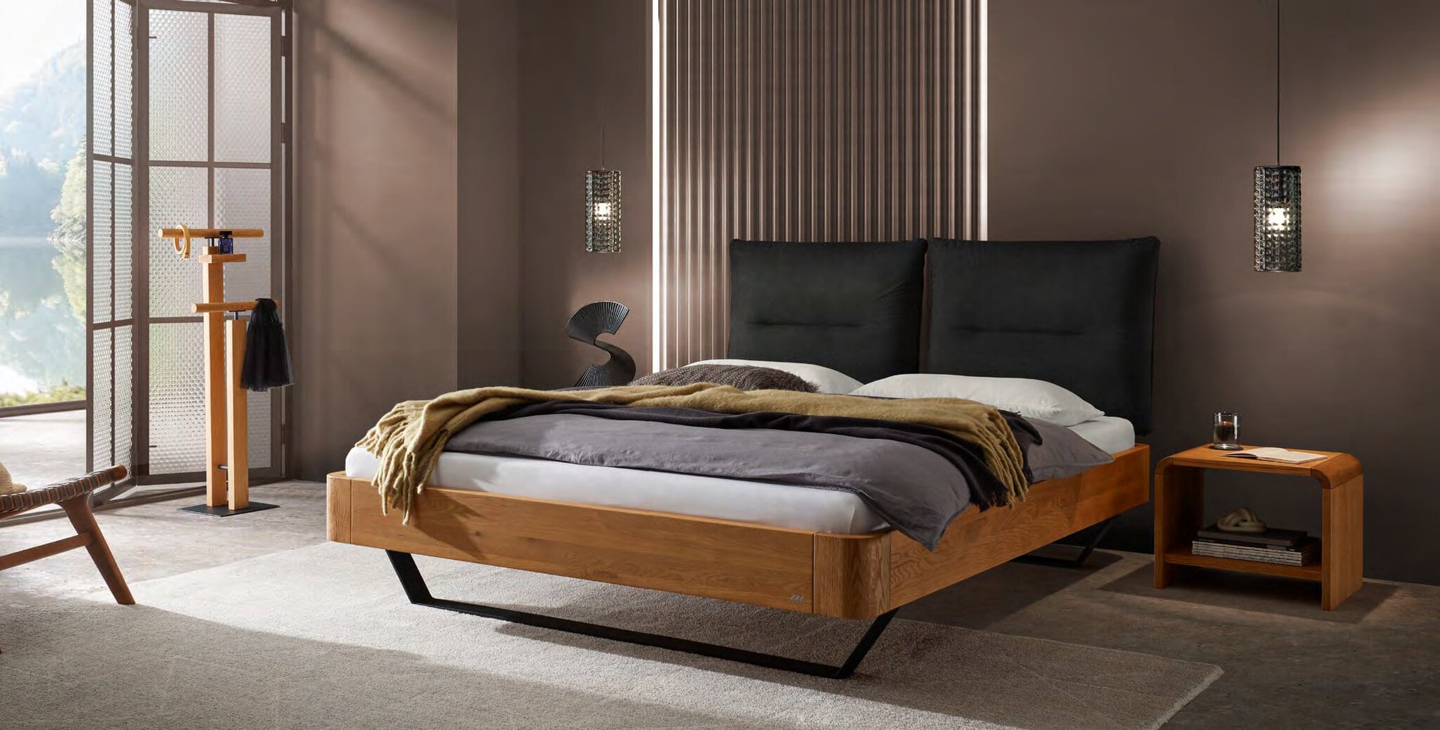 Hasena Oak-Line Bett aus Eiche mit schwarzem Polster-Kopfteil und Stahlkufen im Schlafzimmer