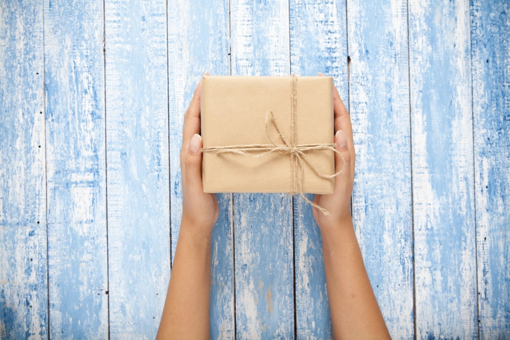 Hände halten ein Geschenk in Packpapier