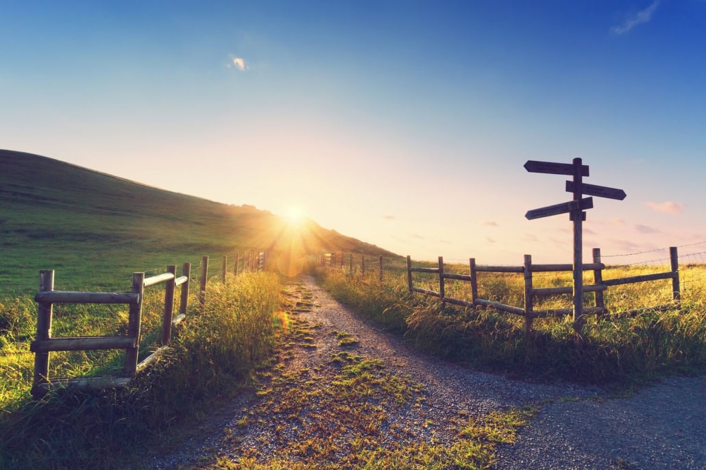 Wegweiser an einem Feldweg im Sonnenlicht